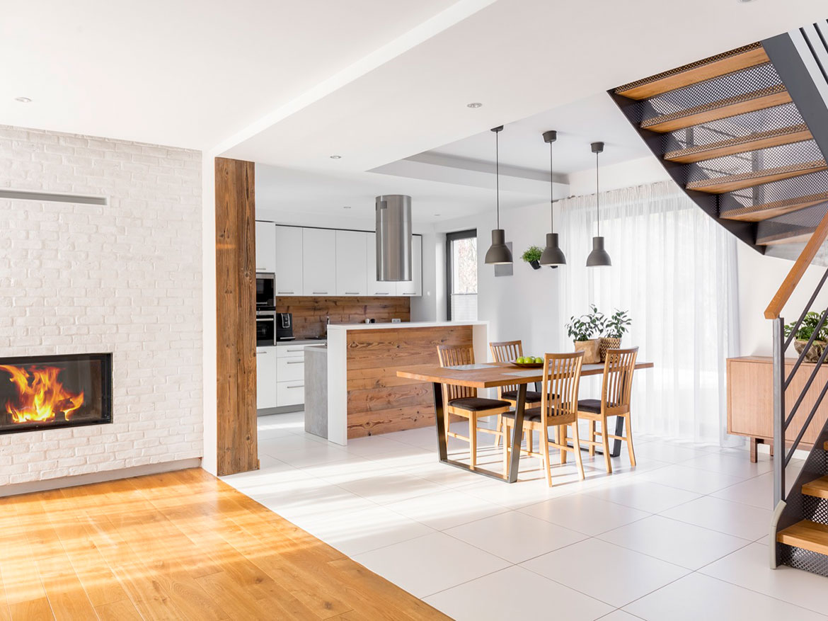 Interior view of a modern kitchen and dining area featuring wooden furniture and a fireplace.