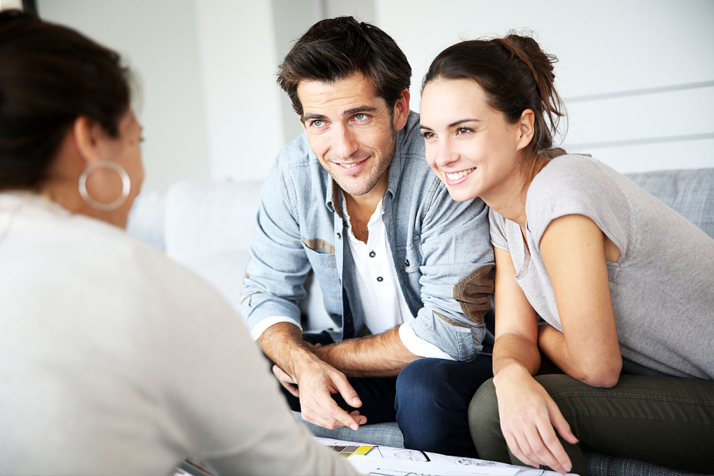 A man and woman smiling while engaged in conversation with another woman in a casual setting.