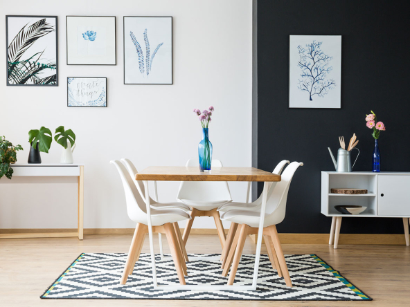Dining room featuring a wooden table, white chairs, and framed artwork on the walls.