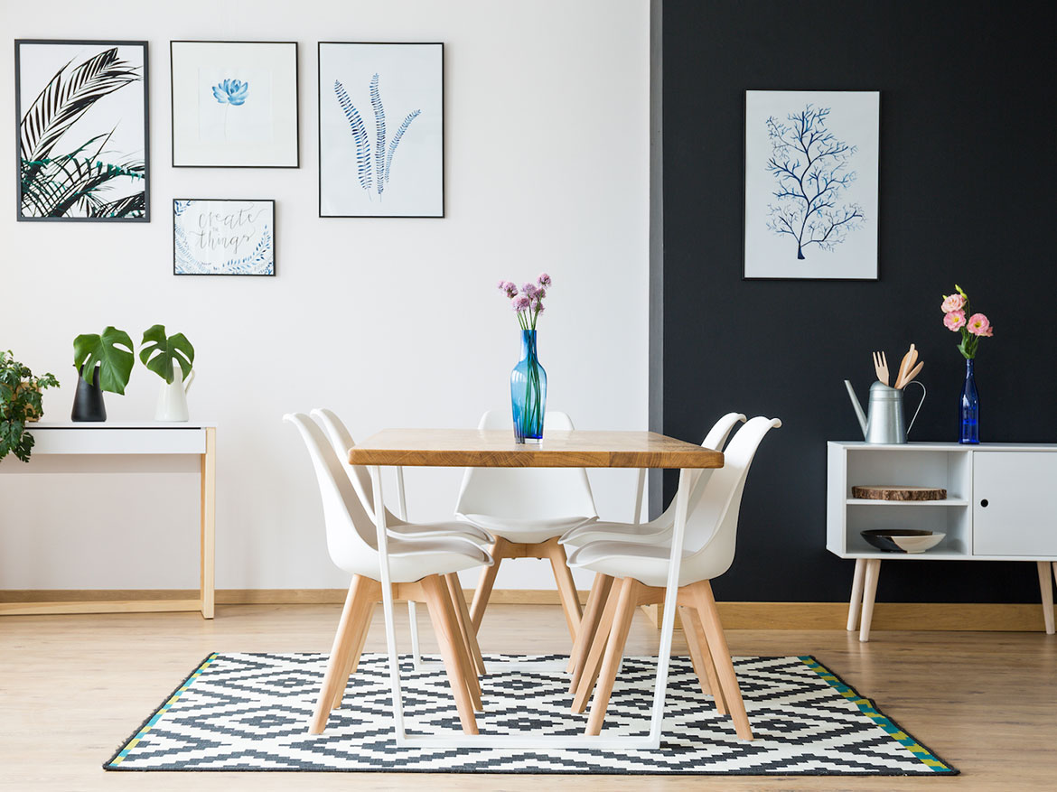 Dining room featuring a wooden table, white chairs, and framed artwork on the walls.